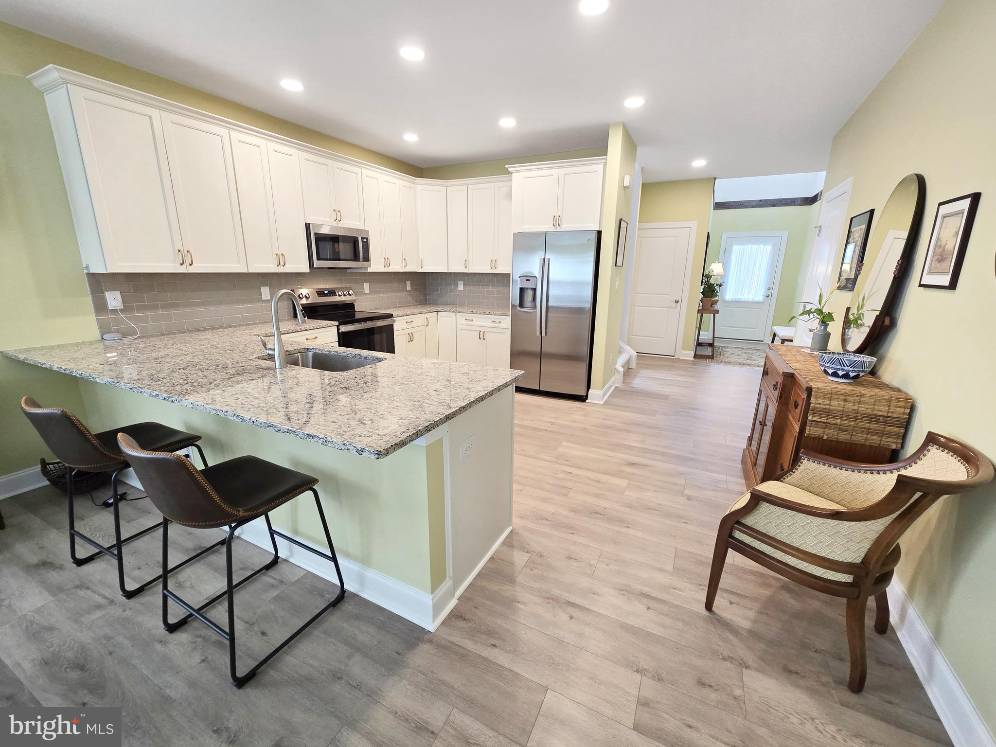 33768 Catching Cove Lewes, DE 19958 - Photo 23 of 69 a kitchen with stainless steel appliances kitchen island granite countertop a table chairs sink refrigerator and microwave