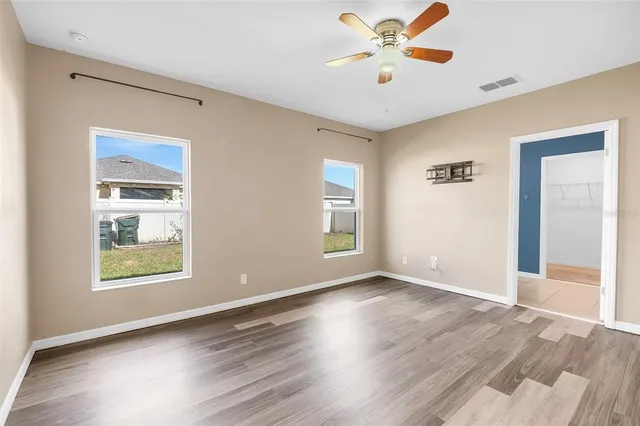 an empty room with wooden floor and windows