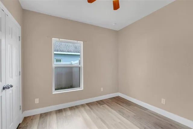 an empty room with wooden floor and ceiling fan