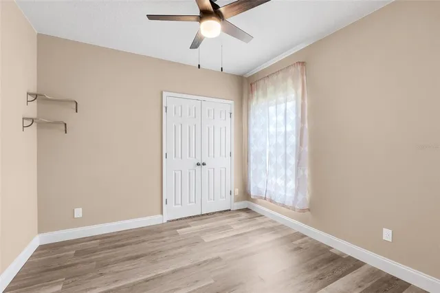 an empty room with a ceiling fan and wooden floor