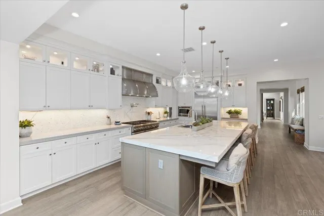 a large kitchen with kitchen island a stove a sink a refrigerator and a wooden floor