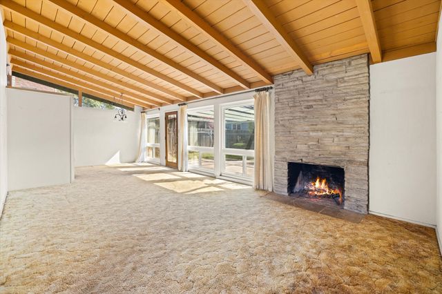 a view of an empty room with a window and a fireplace