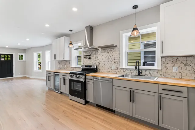 a kitchen with stainless steel appliances granite countertop a sink a stove and a wooden floors