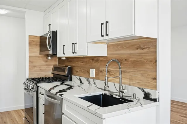 a kitchen with a sink stove top oven and cabinets