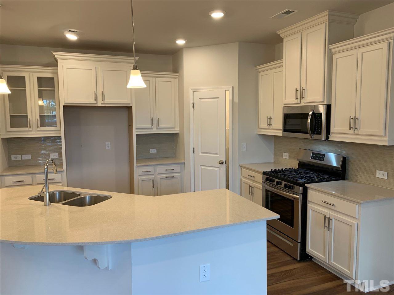 6102 Beale Loop, Unit 104 Raleigh, NC 27616 - Photo 4 of 29 a kitchen with kitchen island a sink a stove and refrigerator
