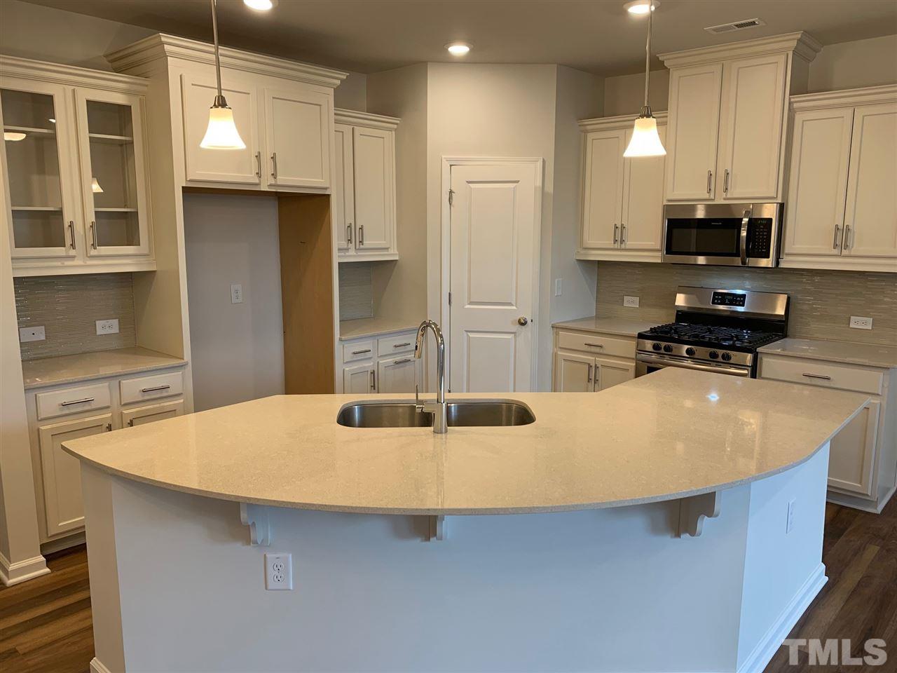 6102 Beale Loop, Unit 104 Raleigh, NC 27616 - Photo 5 of 29 a kitchen with stainless steel appliances a stove a sink and a refrigerator