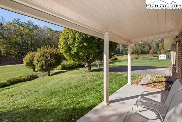a view of a backyard with couches plants and large tree
