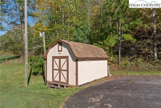 a view of backyard with a barn and large trees