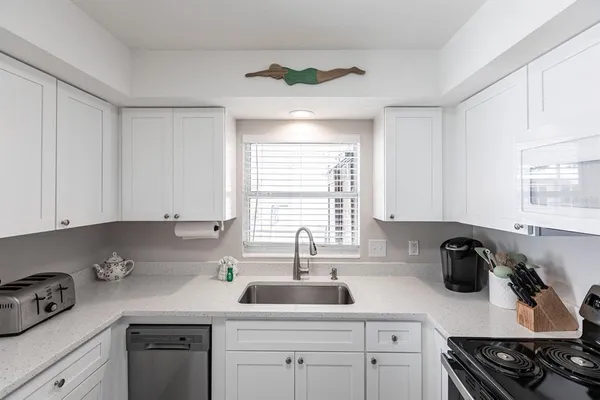 a kitchen with white cabinets and a window