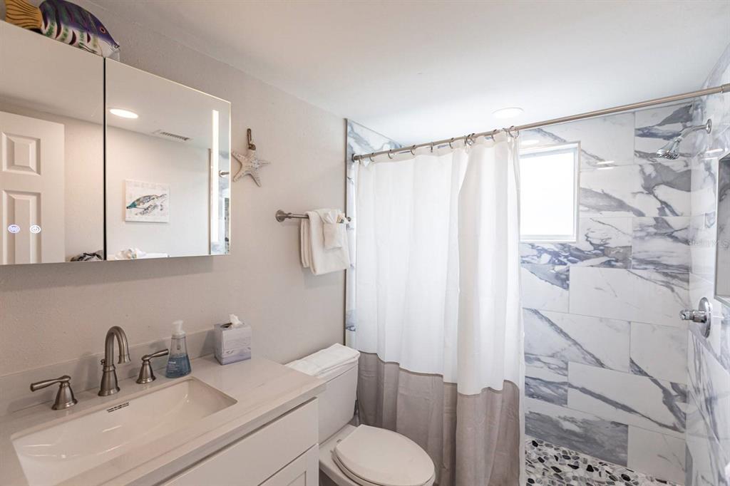 6020 Midnight Pass Road, Unit 52A Sarasota, FL 34242 - Photo 9 of 28 a bathroom with a sink toilet and shower