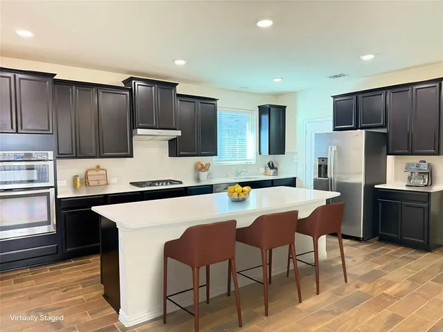 a kitchen with a refrigerator a stove a microwave and island with wooden floor