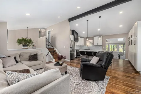 a living room with furniture kitchen and a wooden floor