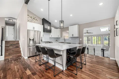 a kitchen with stainless steel appliances a table chairs wooden floors and a view of living room