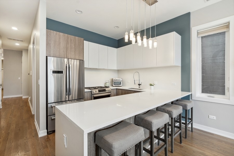 2437 West Haddon Avenue, Unit 2 Chicago, IL 60622 - Photo 7 of 14 a kitchen with a table chairs refrigerator and cabinets