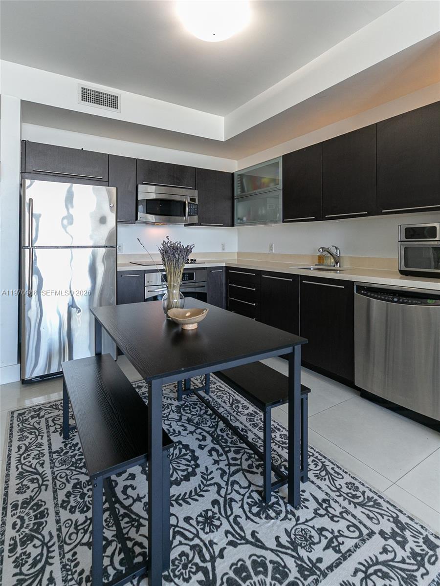 90 Southwest 3rd Street, Unit 1611 Miami, FL 33130 - Photo 14 of 44 a kitchen with stainless steel appliances kitchen island granite countertop a sink and a stove