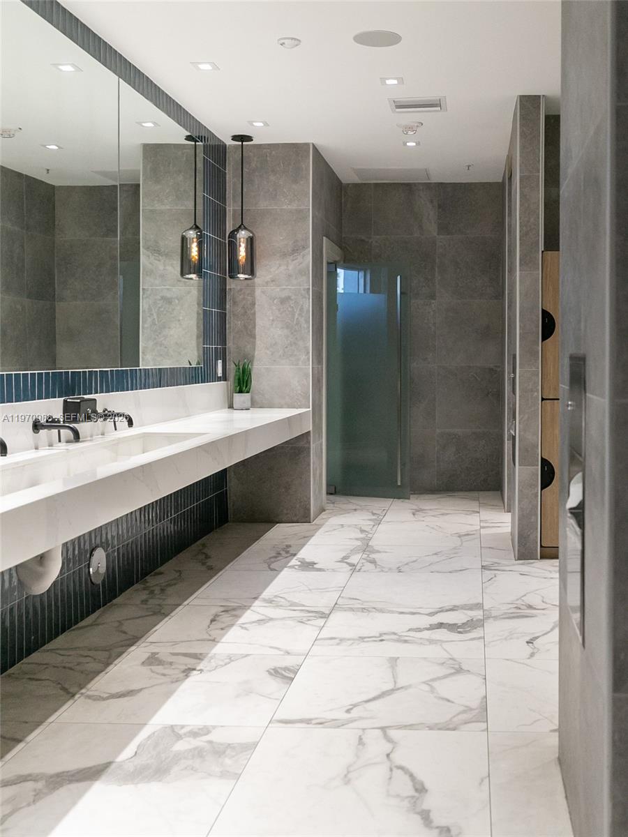 90 Southwest 3rd Street, Unit 1611 Miami, FL 33130 - Photo 34 of 44 a bathroom with a double vanity sink a large mirror and shower