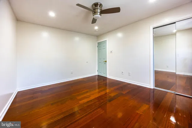 an empty room with wooden floor and ceiling fan