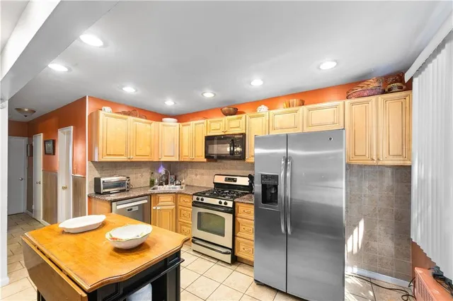 a kitchen with stainless steel appliances granite countertop a refrigerator a sink a stove and oven