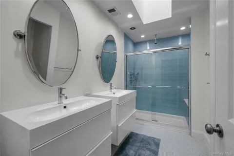 a en suite bathroom with a double vanity sink mirror and shower