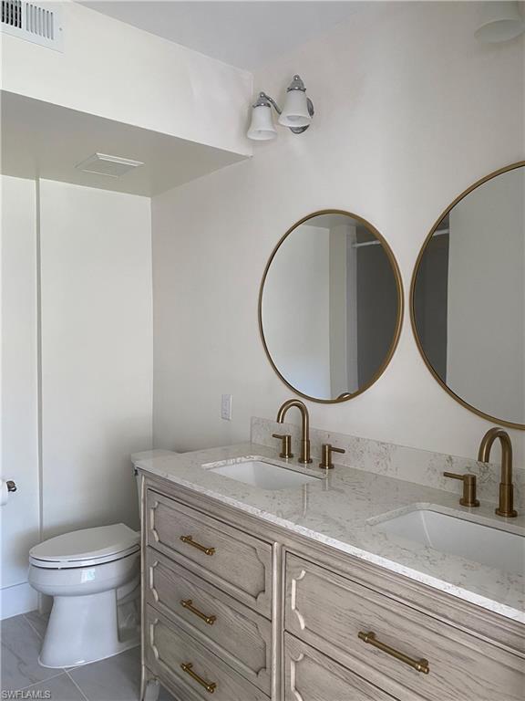 137 Wading Bird Circle, Unit F101 Naples, FL 34110 - Photo 6 of 16 a bathroom with a toilet a sink and mirror