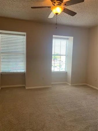 an empty room with windows and fan