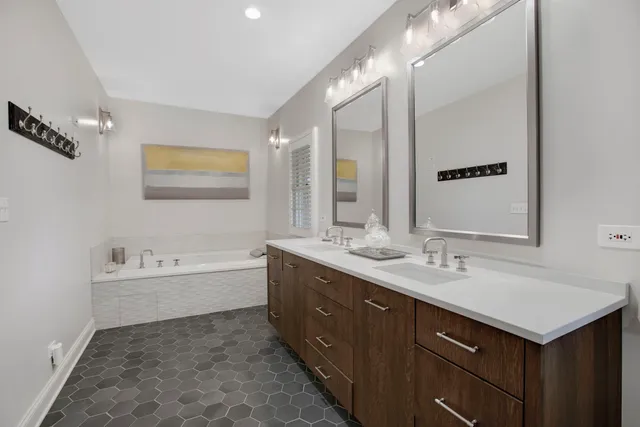 a bathroom with a double vanity sink mirror and bathtub