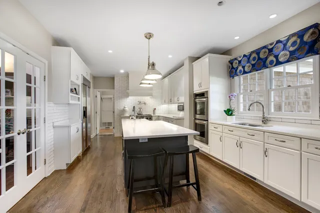 a kitchen with stainless steel appliances kitchen island granite countertop a table chairs sink and cabinets