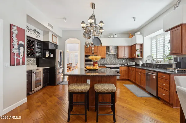 a kitchen with stainless steel appliances granite countertop a stove a refrigerator a kitchen island a dining table and chairs with wooden floor