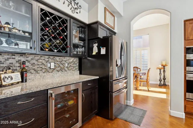 a kitchen with stainless steel appliances granite countertop a stove a refrigerator a sink dishwasher a dining table and chairs with wooden floor