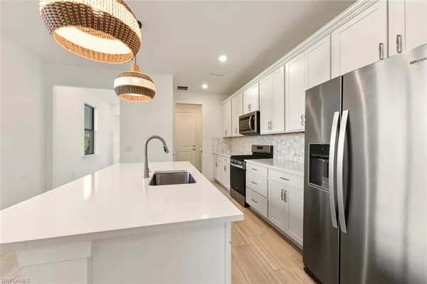 a kitchen with refrigerator a stove a sink and dishwasher with wooden floor