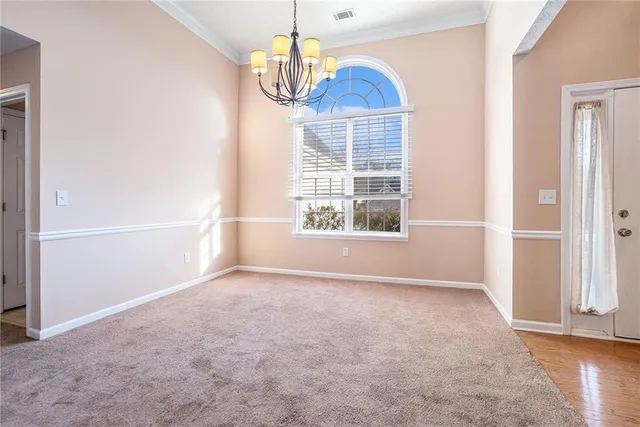 an empty room with chandelier front door and windows