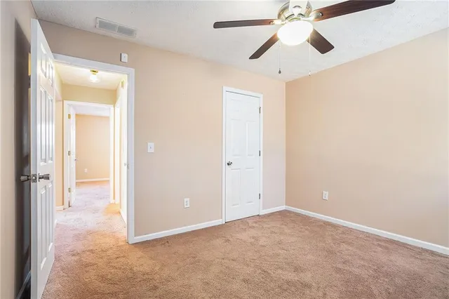 an empty room with closet and a chandelier fan