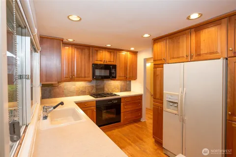 a large kitchen with stainless steel appliances a refrigerator a sink a stove top oven and cabinets