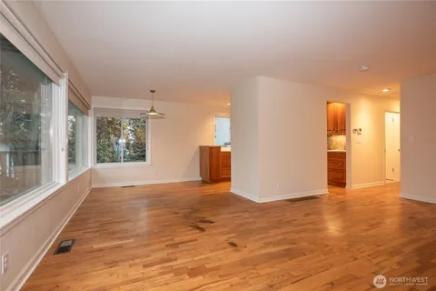 a view of an empty room with window and wooden floor