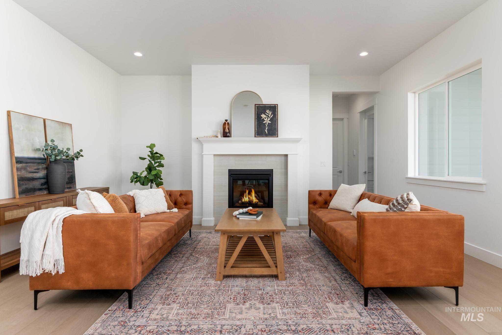 8501 South Country Wind Avenue Meridian, ID 83642 - Photo 4 of 39 Living area featuring a central fireplace with a classic white mantel, light-toned tile surround, and an integrated firebox