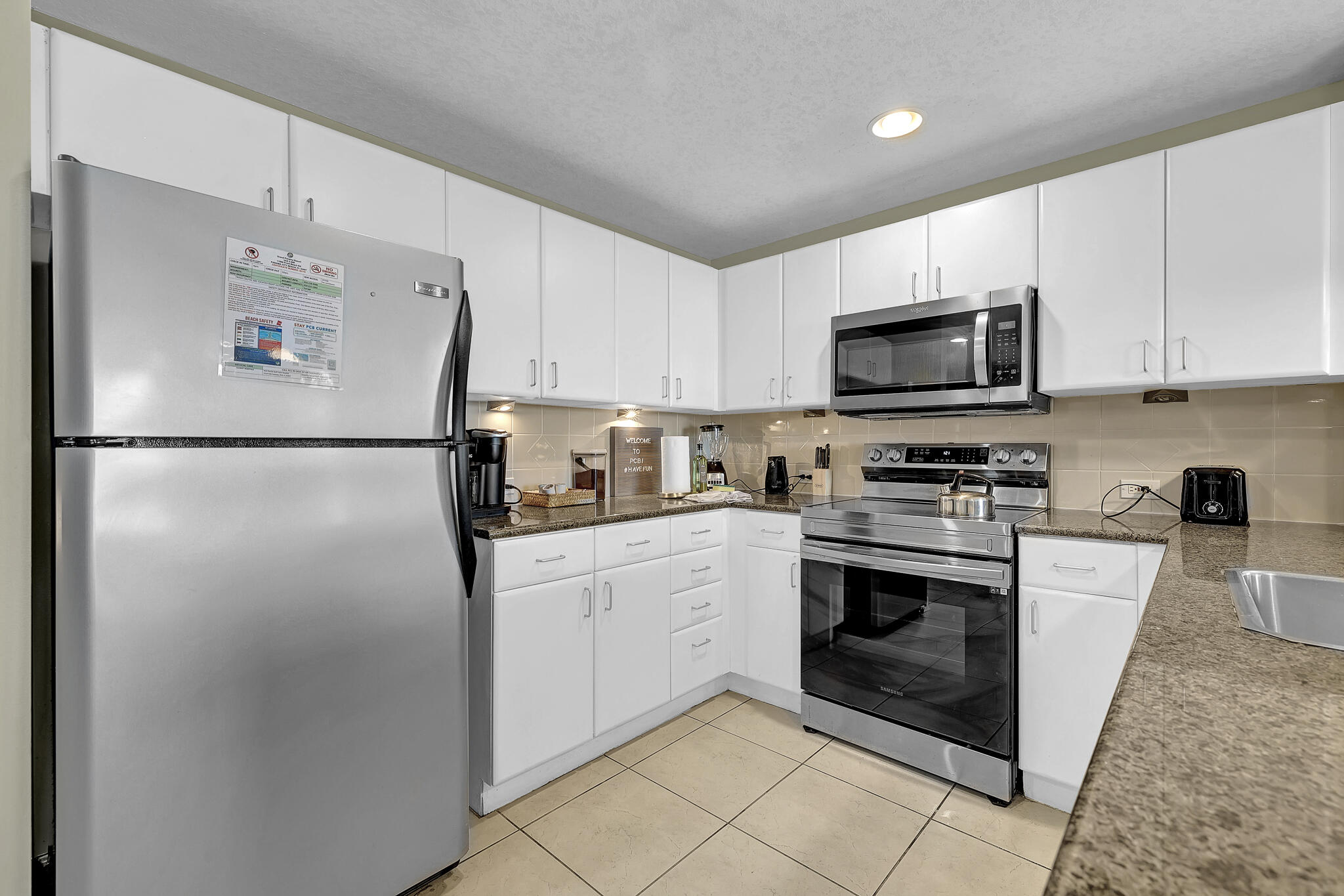 11800 Front Beach Road, Unit 2408 Panama City Beach, FL 32407 - Photo 10 of 42 a kitchen with stainless steel appliances granite countertop a refrigerator stove a sink and a microwave