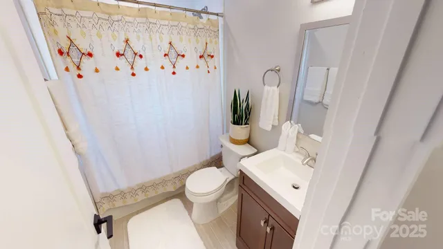 a white toilet sitting next to a white sink and a shower curtain