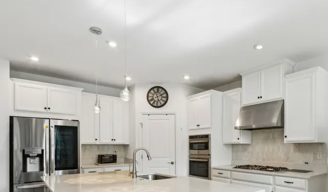 a kitchen with stainless steel appliances a stove and white cabinets