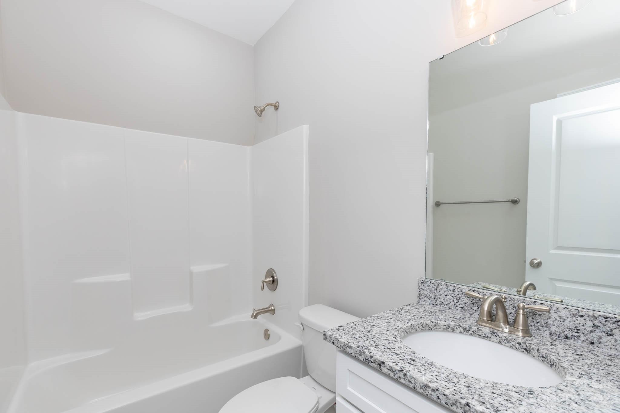 4639 Simpson Road Edgemoor, SC 29712 - Photo 16 of 30 a bathroom with a granite countertop sink a toilet and bathtub