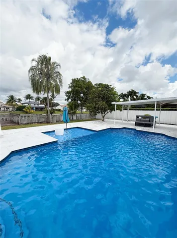a view of a swimming pool with a patio and palm trees