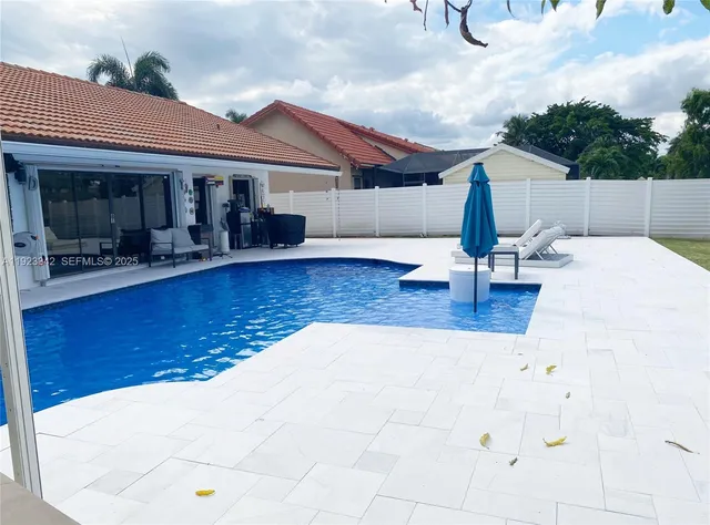 a swimming pool with outdoor seating and barbeque oven