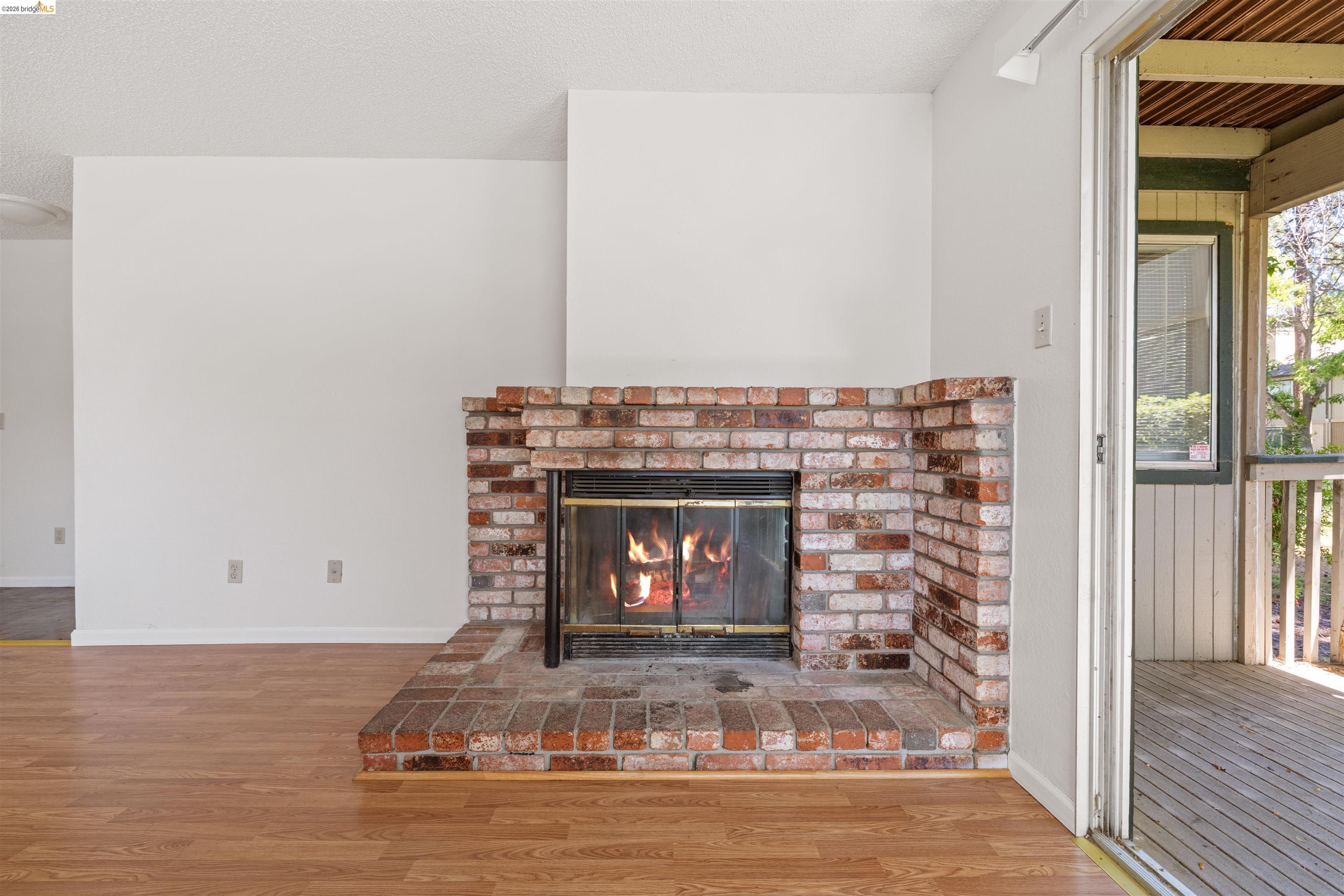 1151 Chadwick Circle Bay Point, CA 94565 - Photo 5 of 23 Brick fireplace with a hearth, wood-finish flooring, white walls, and a sliding glass door leading to an outdoor deck