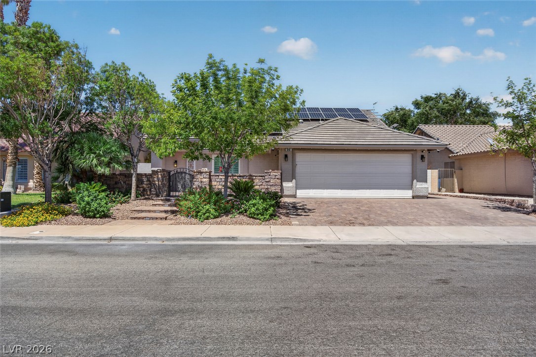 818 Manor Shores Road Henderson, NV 89002 - Photo 2 of 35 Mature trees and lush landscaping frame this inviting residence, featuring an attached garage and a charming private entrance.