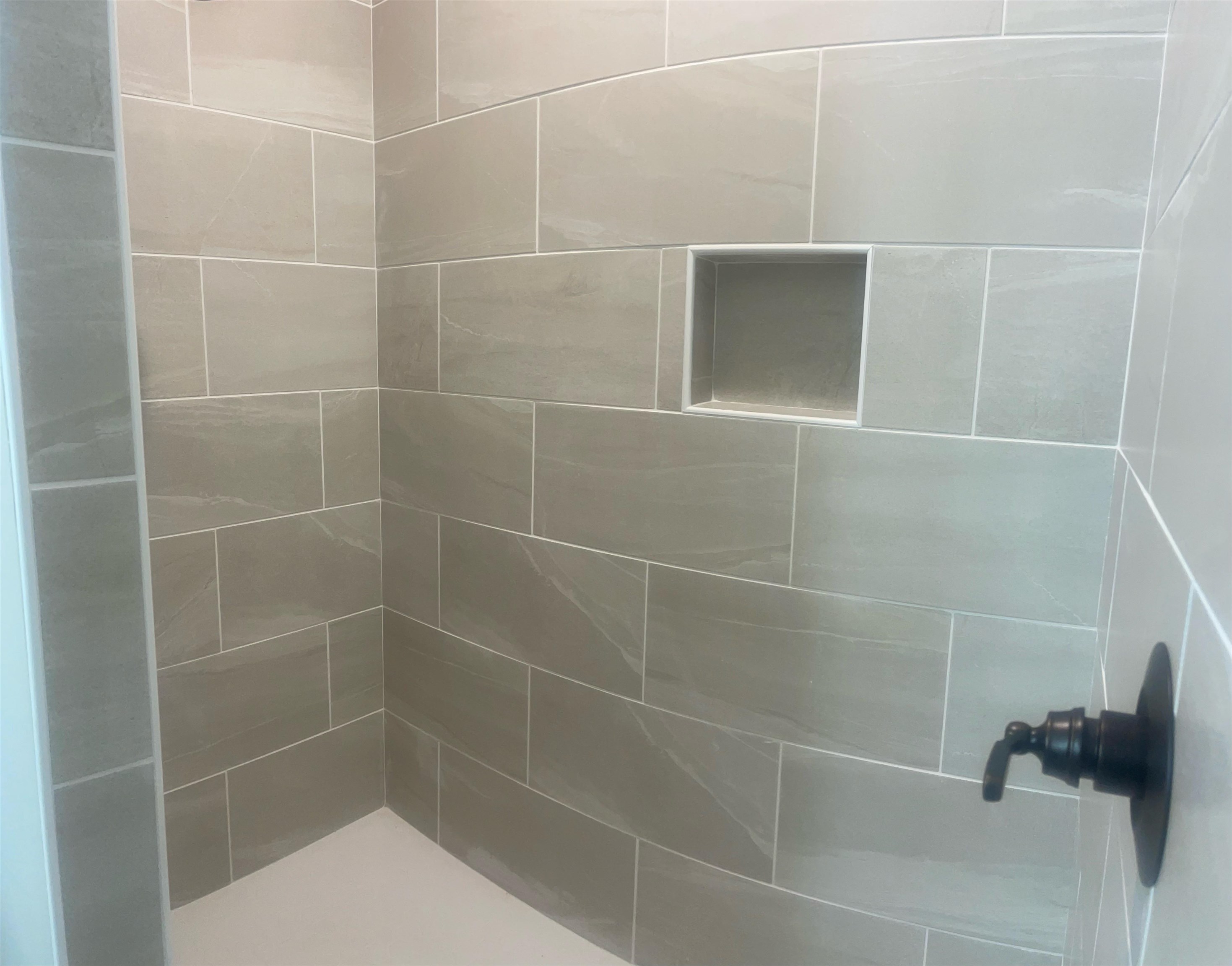 210 Church Street Ripley, TN 38063 - Photo 12 of 21 Shower enclosure featuring grey rectangular tiles, a built-in shower niche, and a matte black shower fixture
