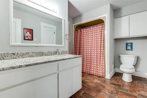 a bathroom with a granite countertop toilet and a sink