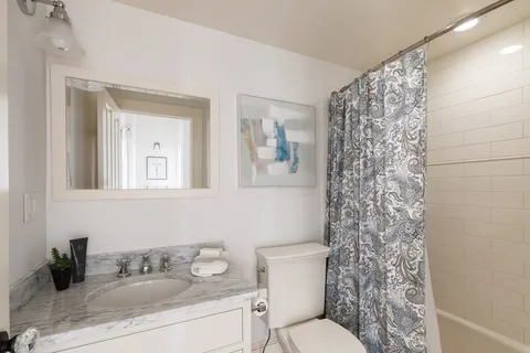 a bathroom with a granite countertop sink a toilet and a mirror
