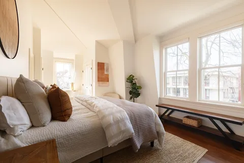 a bedroom with a bed a chandelier and a window