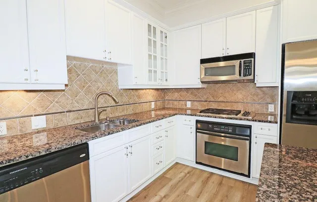 a kitchen with granite countertop white cabinets stainless steel appliances and a sink