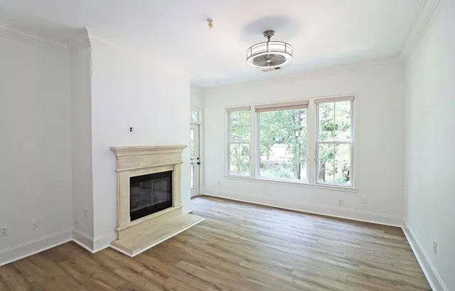 an empty room with wooden floor fireplace and windows