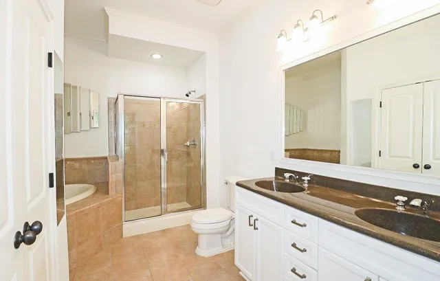a bathroom with a granite countertop sink a toilet a mirror and shower